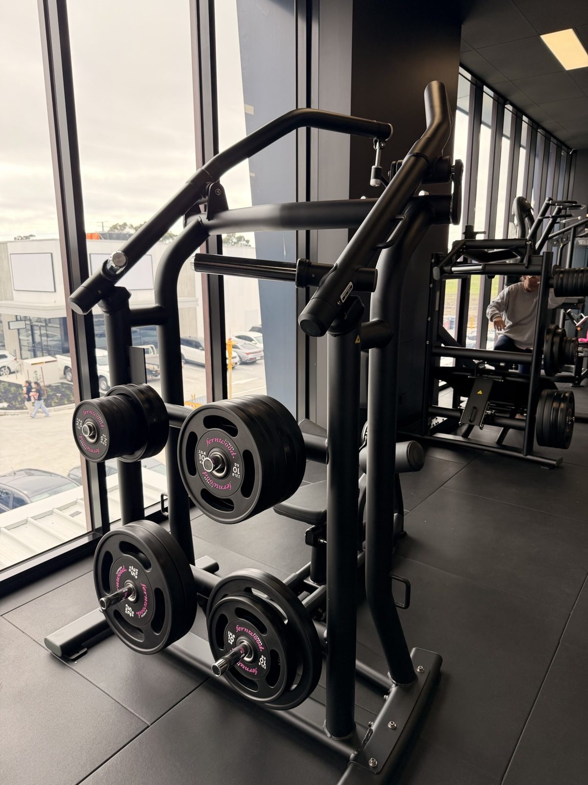 Plate-loaded strength machine stacked with Fernwood-branded Olympic plates