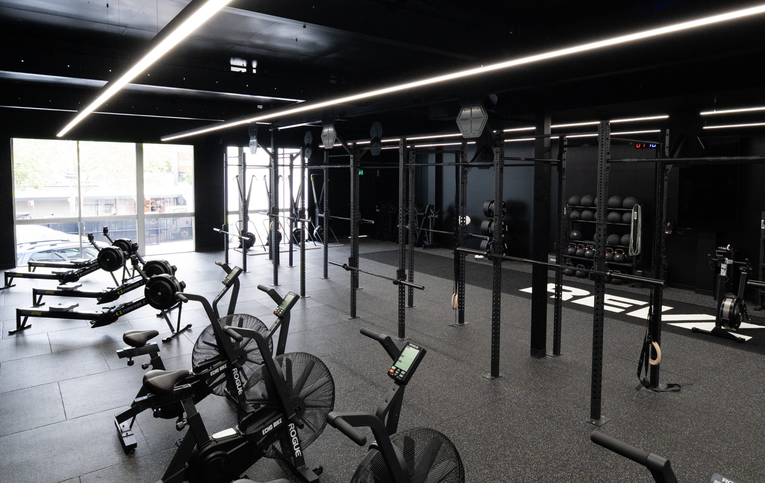 REVL studio floor with rigs, Concept2 RowErgs, air bikes and wall-ball storage